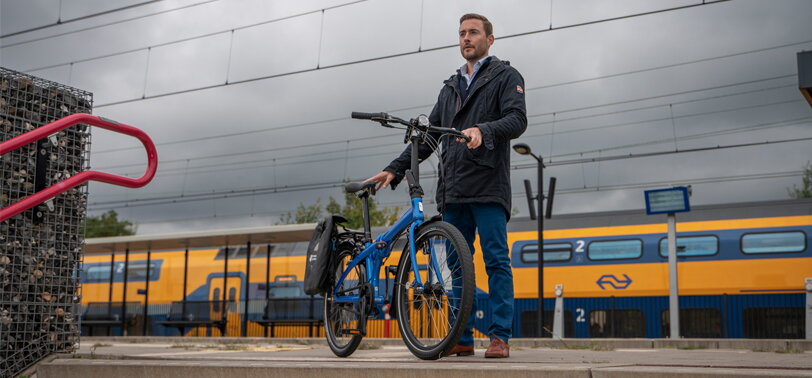 Man staat met fiets op het perron en op de achtergrond rijdt een NS trein