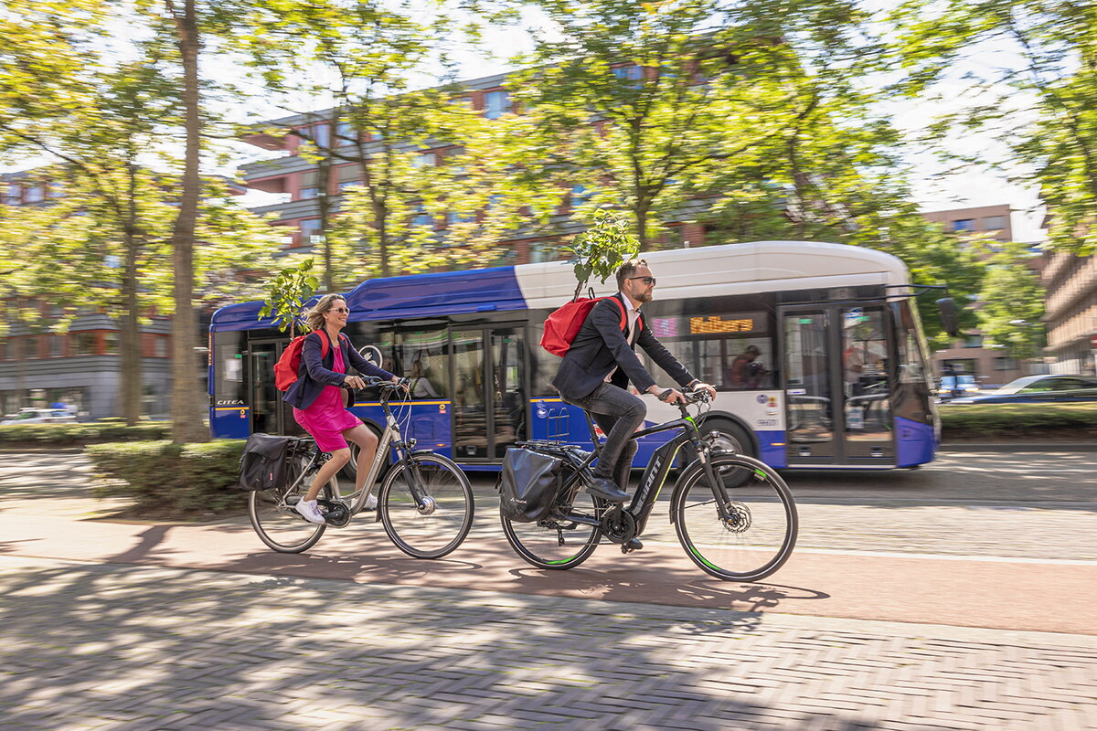 Groen reizen met de elektrische bus van Arriva of op de fiets - twee fietsers met in de rugzak een boompje