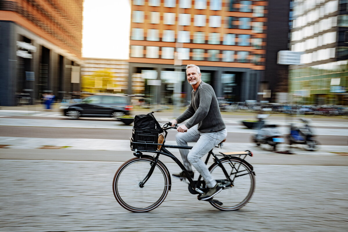 Man op fiets onderweg naar zijn werk door de stad
