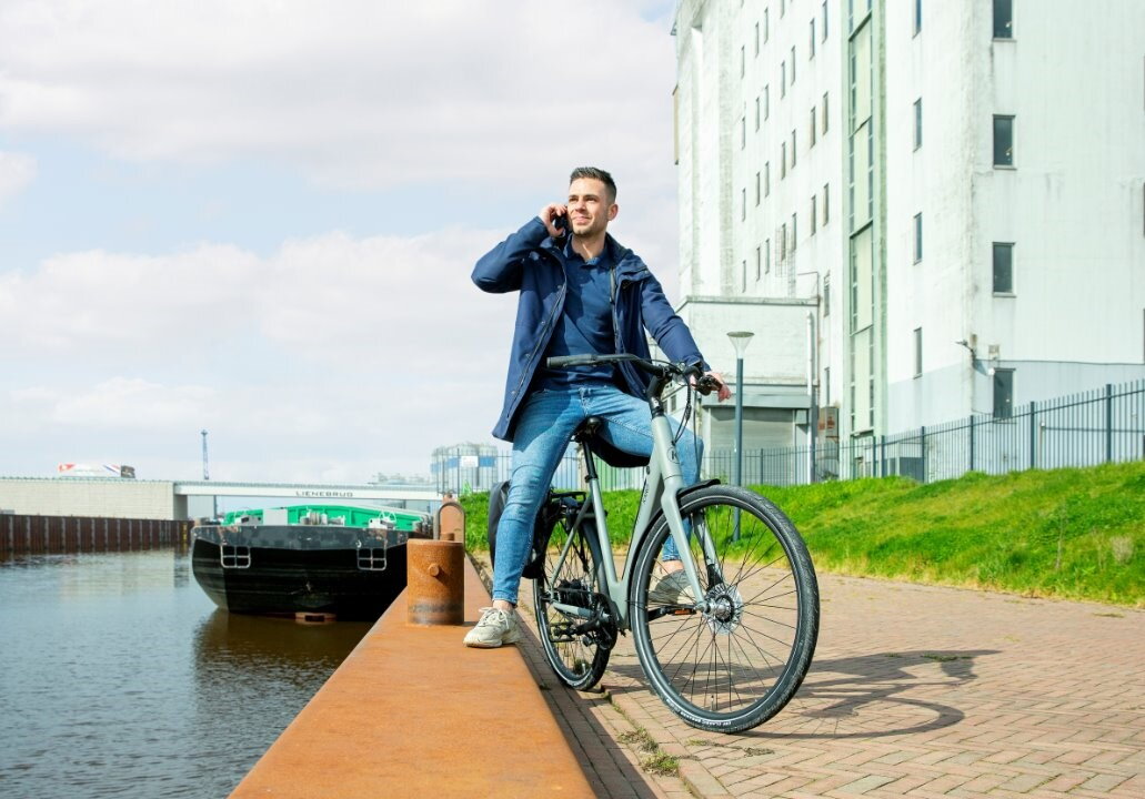 Man op fiets staat stil om te bellen met links van hem water