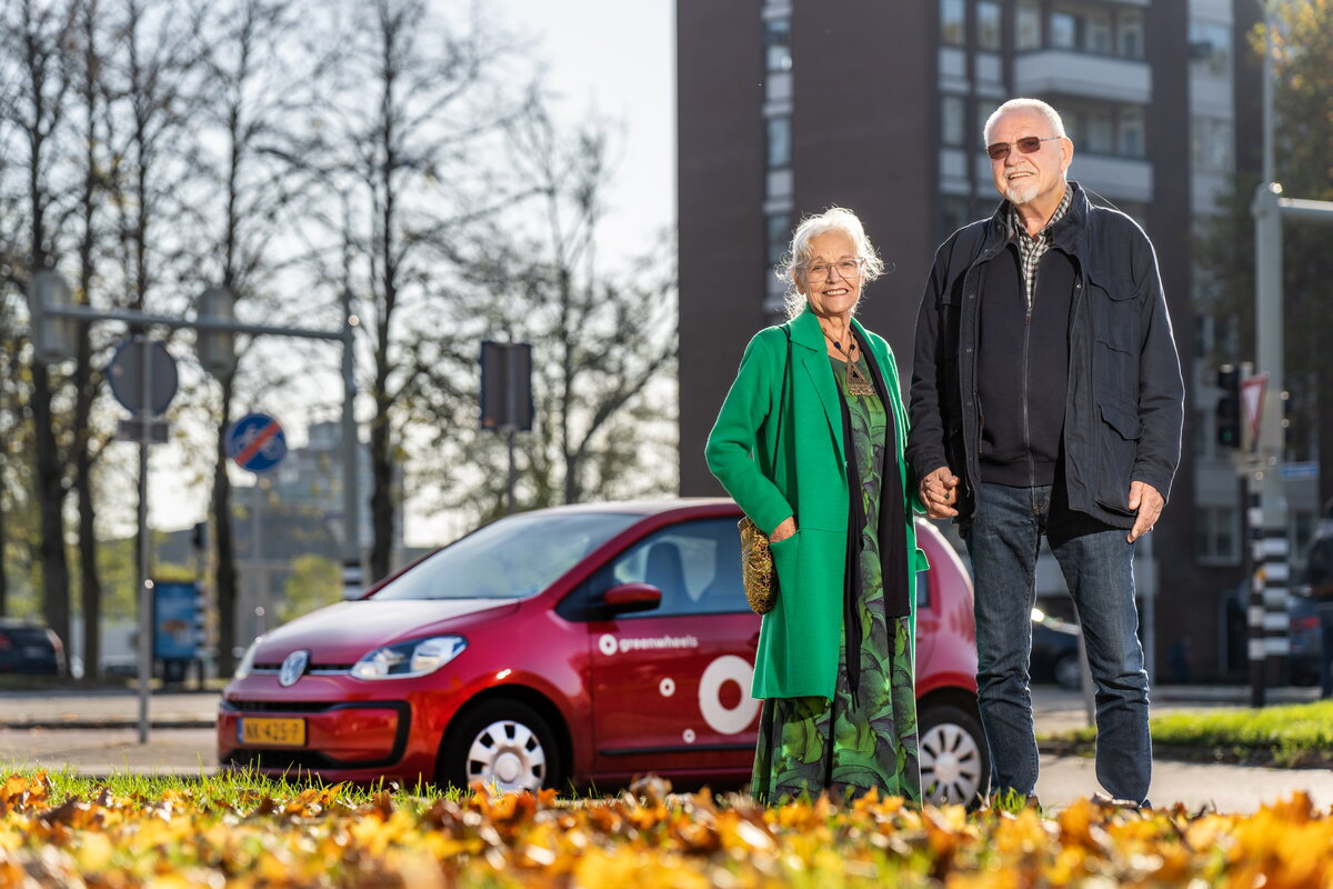 Theo de Vrede samen met zijn vriendin Maria Geelen voor een rode deelauto