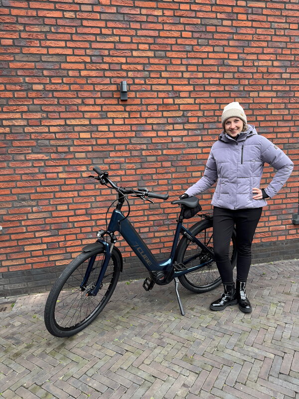 Thalita houdt naar e-bike vast en staat voor een bakstenen muur