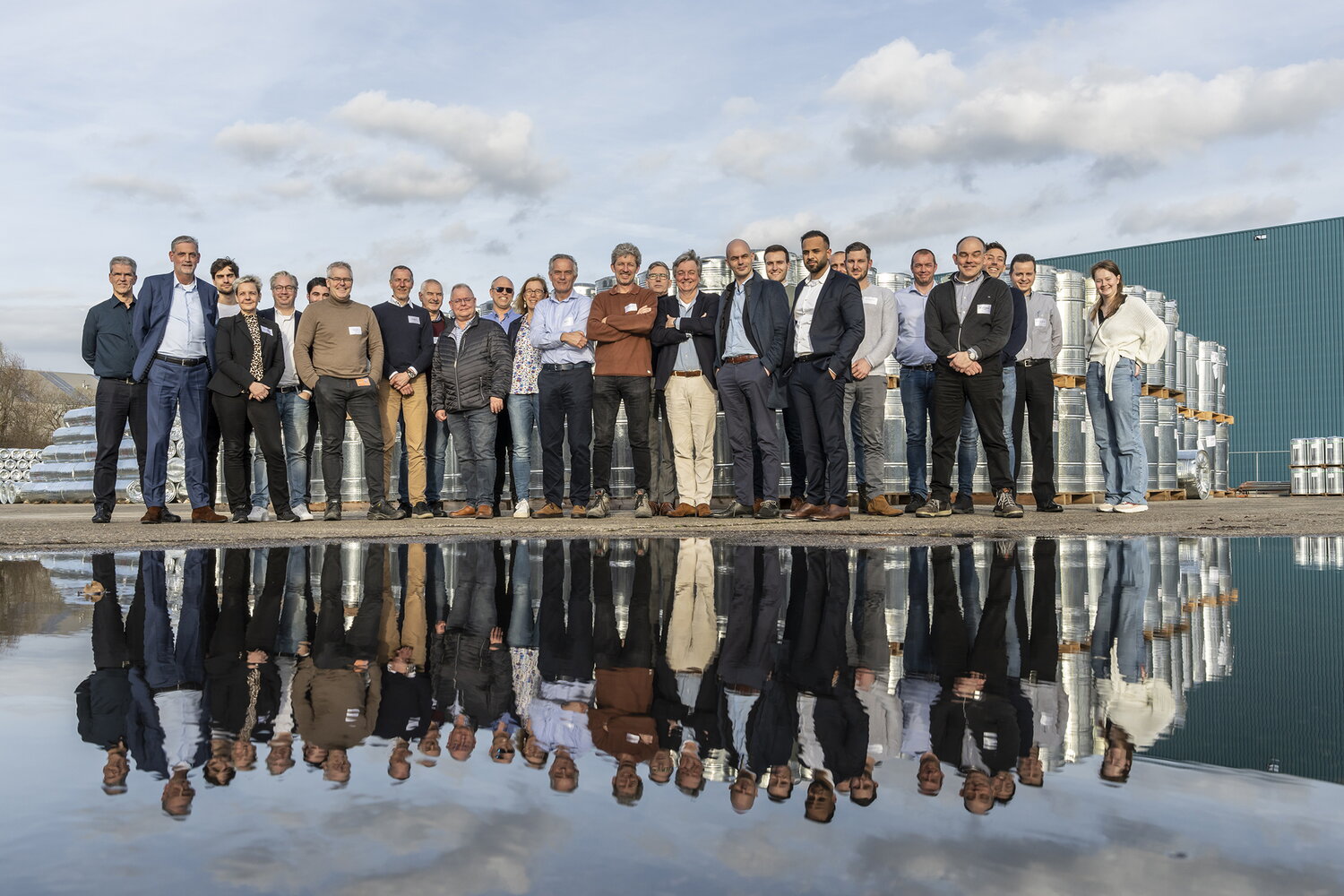 Group photo of MEA participants on 23 March 2023 at Lawter. About 30 men and women are standing side by side in a row, looking at the camera. In the foreground, there is a water feature that reflects the group of people