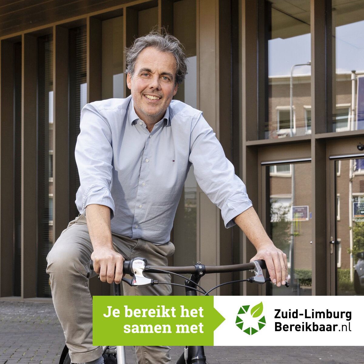 Marcel Noten in grijs hemd op fiets voor Mediahuis Limburg