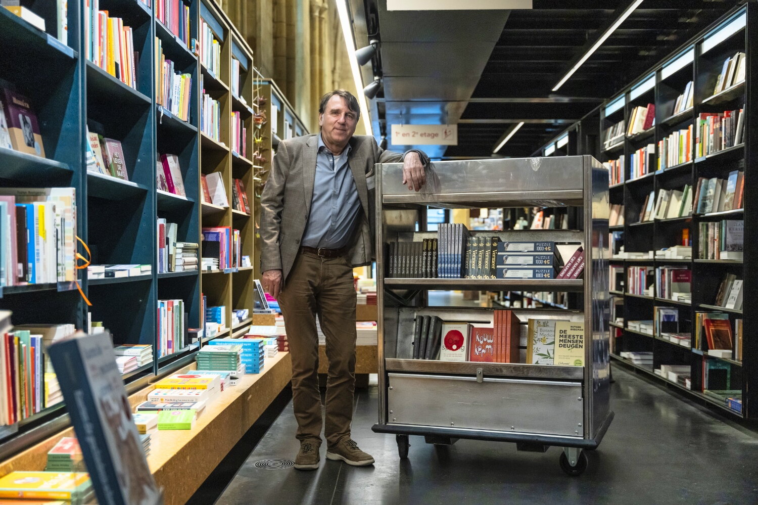 Ton Harmes staat tussen de boekenrekken in Boekhandel Dominicanen
