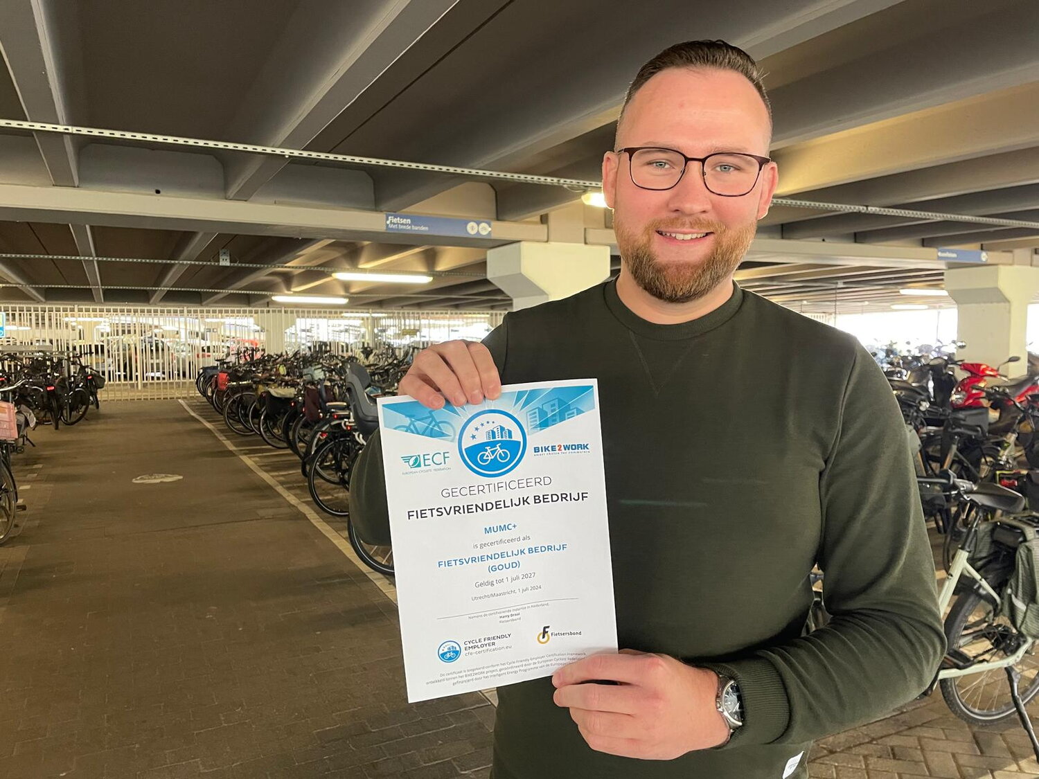 Alexander Knooren houdt het certificaat Fietsvriendelijk Bedrijf vast in de MUMC+ fietsenstalling