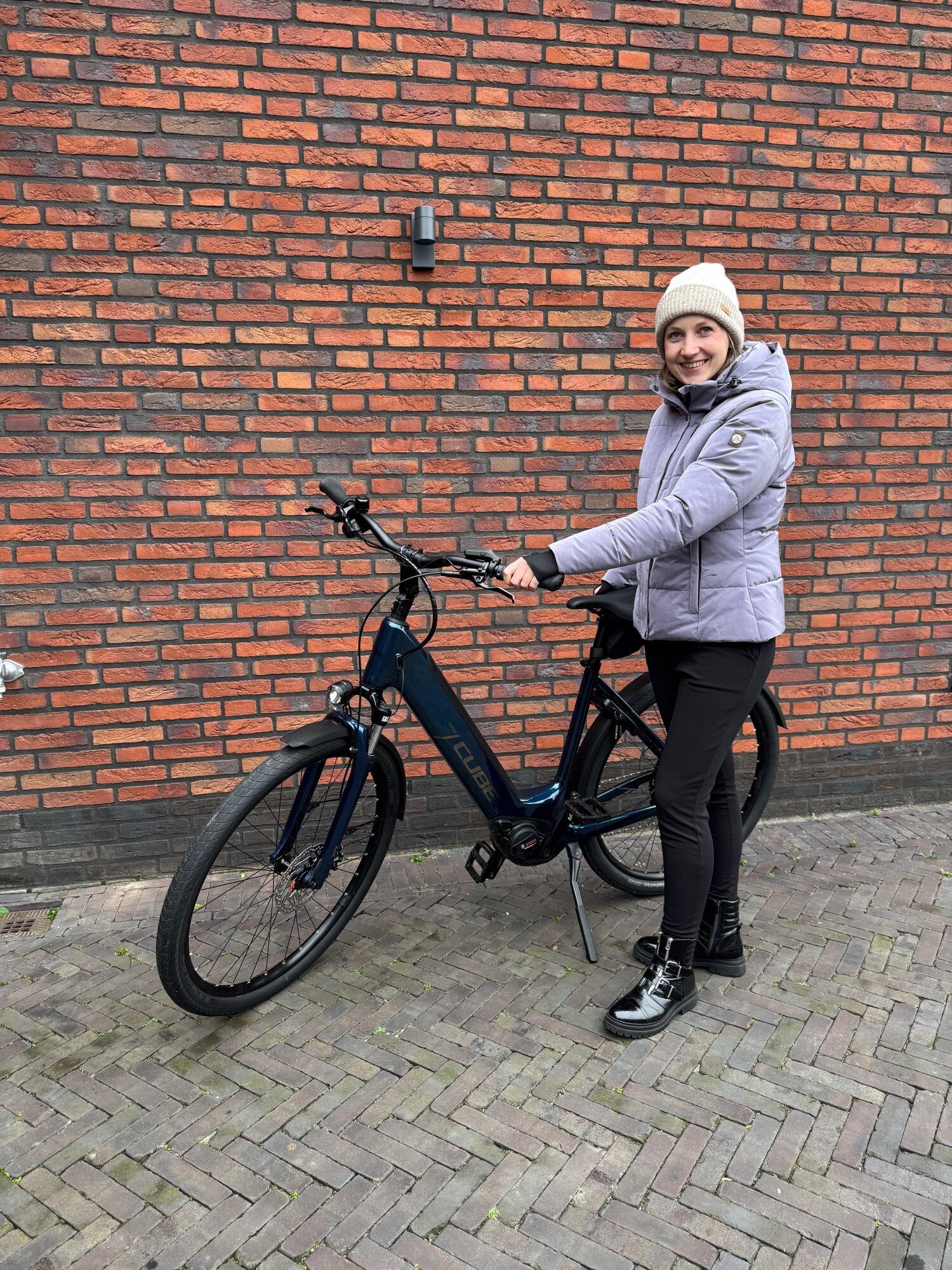 Thalita staat voor een rode muur met haar gewonnen e-bike