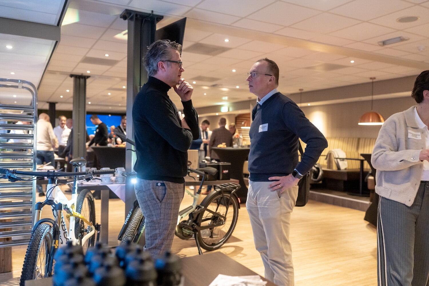 Kick-off Aviation Valley 27 jan 26 - Leverancier van fietsen (man) in gesprek met een van de aanwezigen, een man die er namens een werkgever aanwezig was