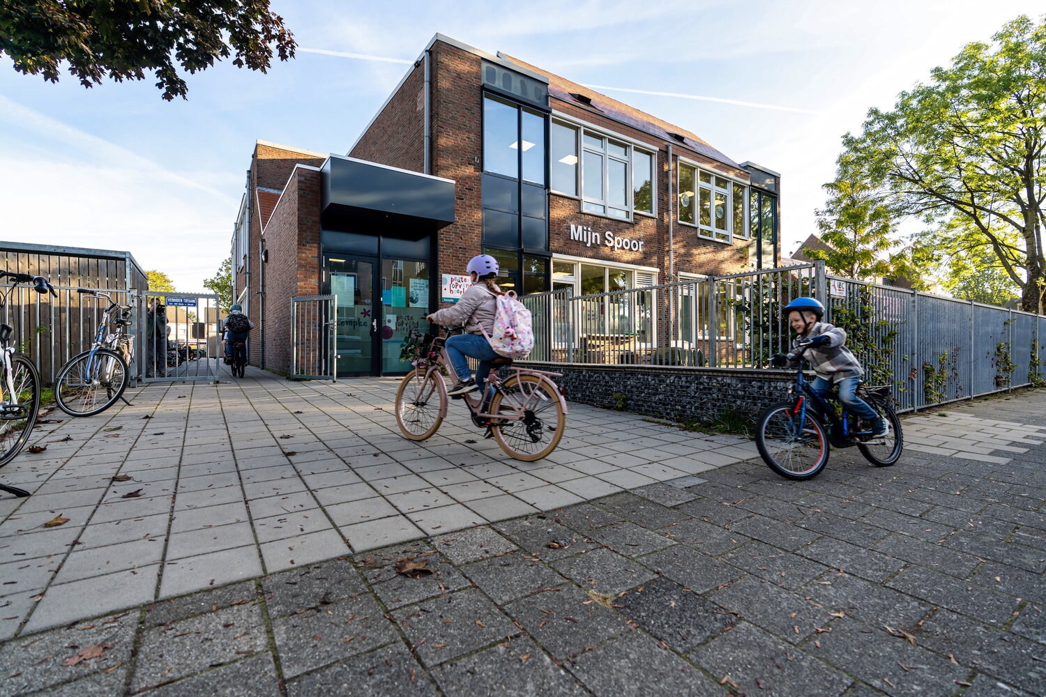 Twee kinderen komen aan op de fiets bij hun basisschool